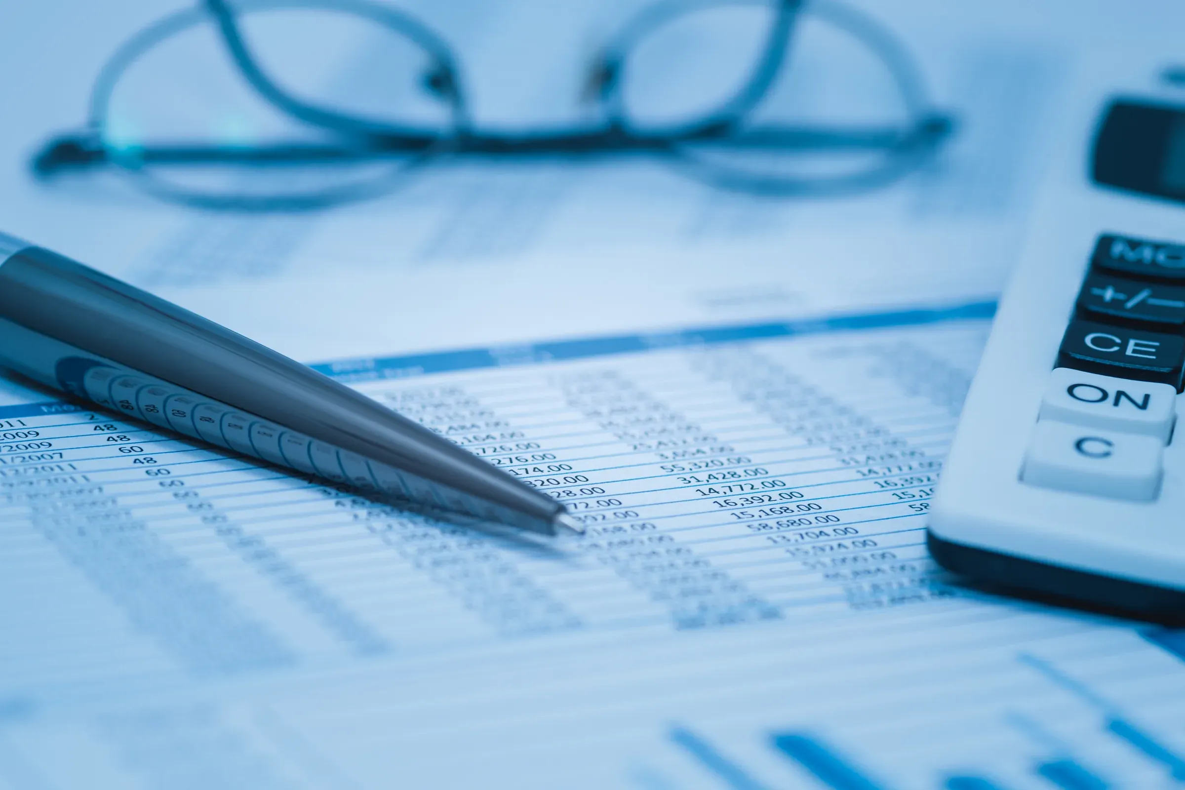 Reading glasses and a calculator resting on a printed financial spreadsheet